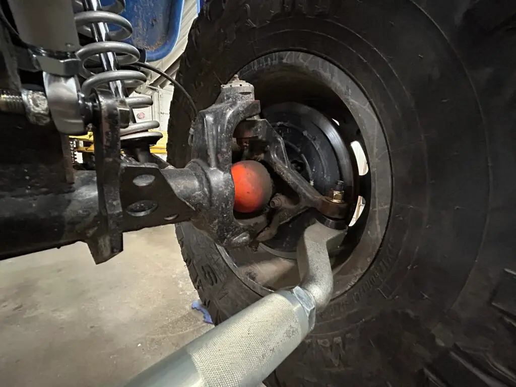 Close-up view of a Jeep's front suspension, showing the steering knuckle connecting to the upper and lower ball joints. One of the main locations of death wobble,