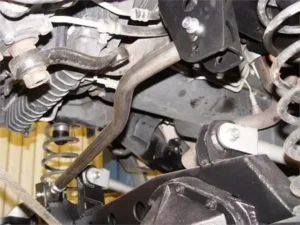 Close-up of a Jeep trackbar with suspension components under the vehicle.
