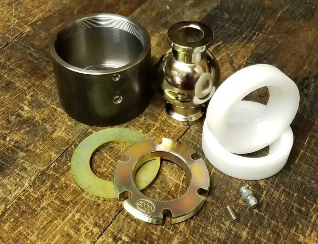 Disassembled Summit Machine flex joint kit with metal housing, spherical joint, washers, and polymer inserts on a wooden surface.