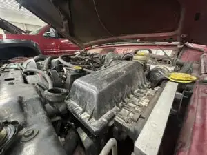 Side-angle view of a Jeep Wrangler's engine bay, showing a closed air filter housing cover ready for maintenance.