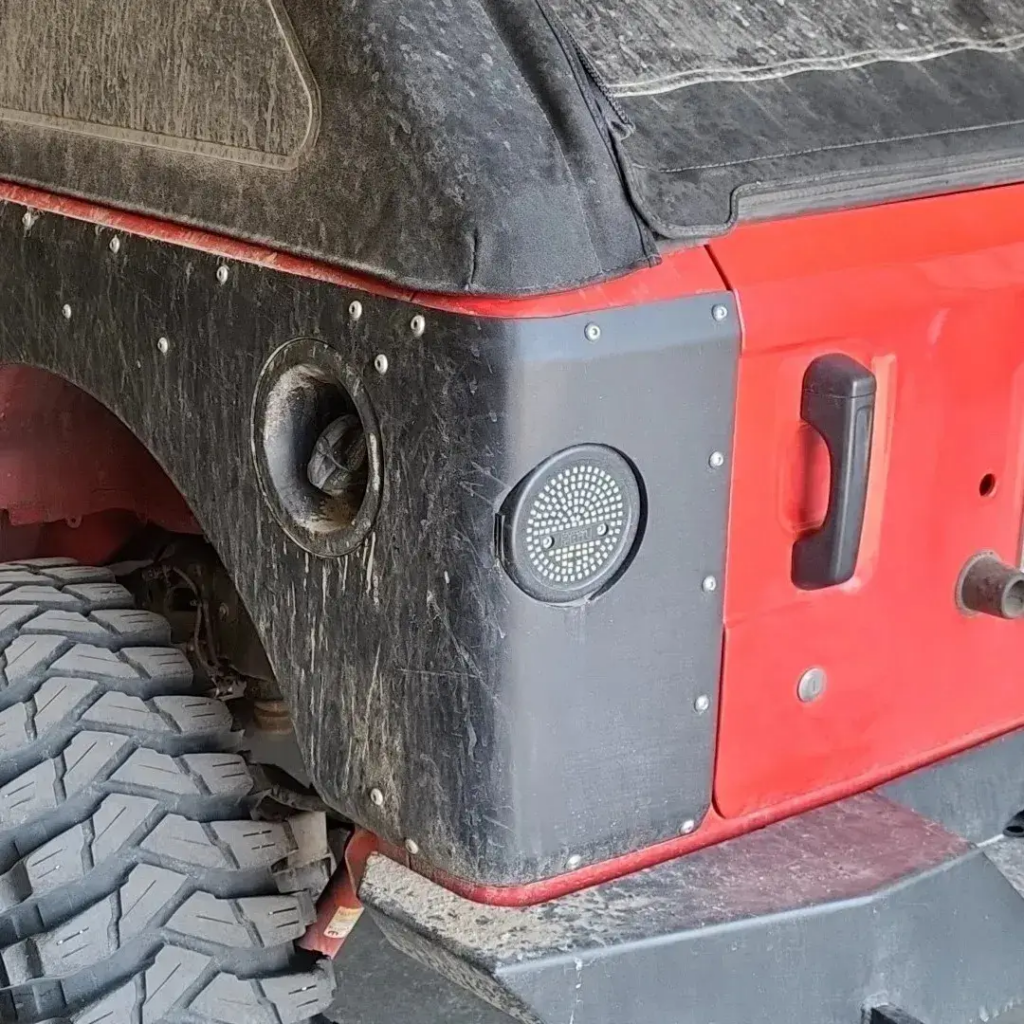 Close-up view of a Jeep’s rear corner featuring TNT Customs corner armor, fuel filler cutout, and round LED tail light.