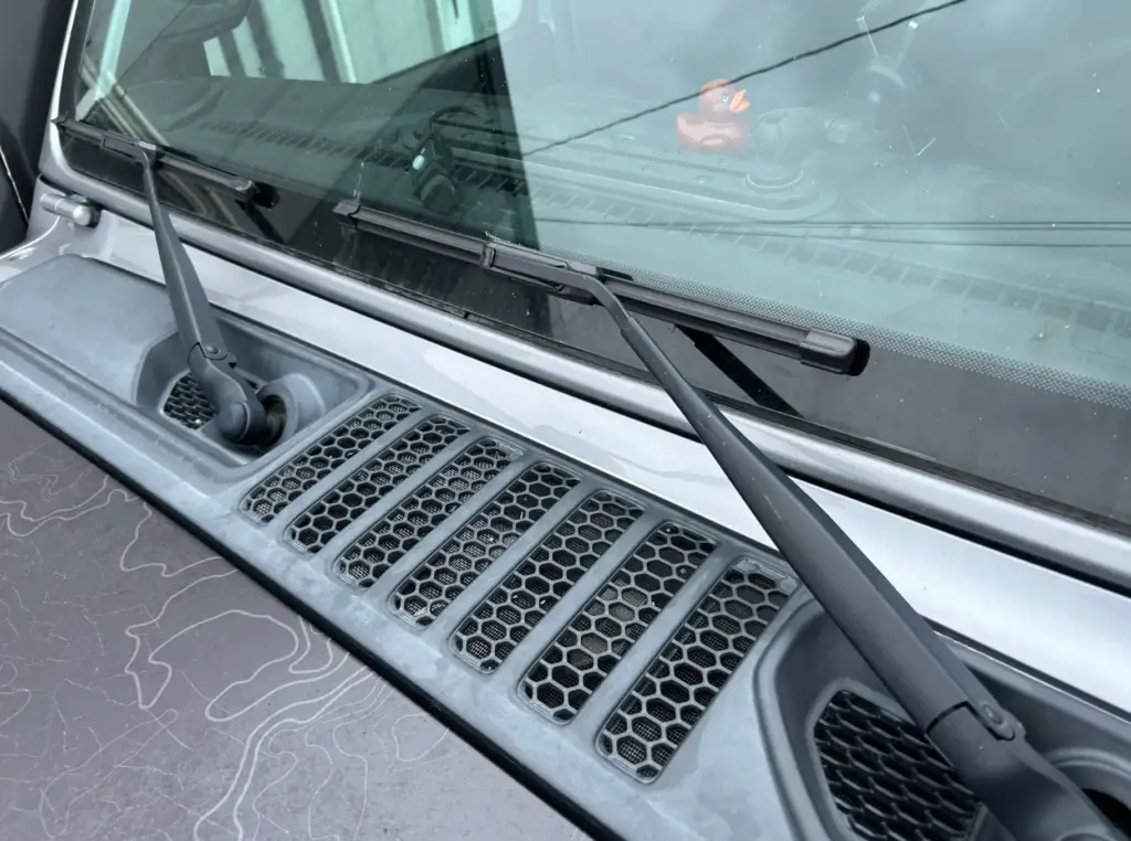 Close-up of windshield wiper blades resting in their normal position on a Jeep windshield.