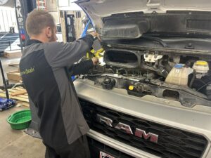 Technician from TNT Customs adds fluid under the hood of a RAM truck in the shop.