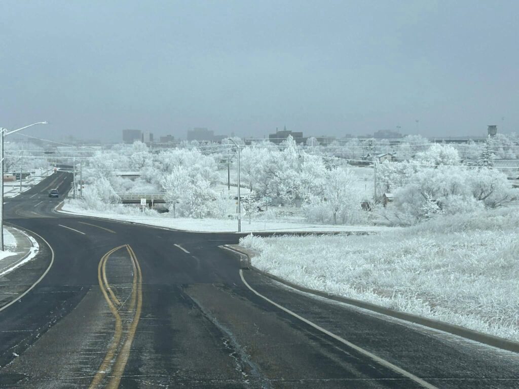Snow-covered winter landscape in Cheyenne, Wyoming, showing icy roads, frost-covered trees, and cold weather driving conditions.
