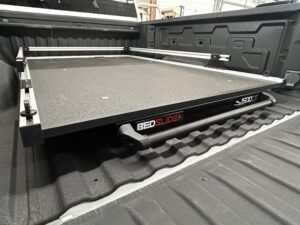 Heavy-duty Bedslide cargo tray installed in a pickup truck bed with spray-in bedliner for easy access to tools and gear