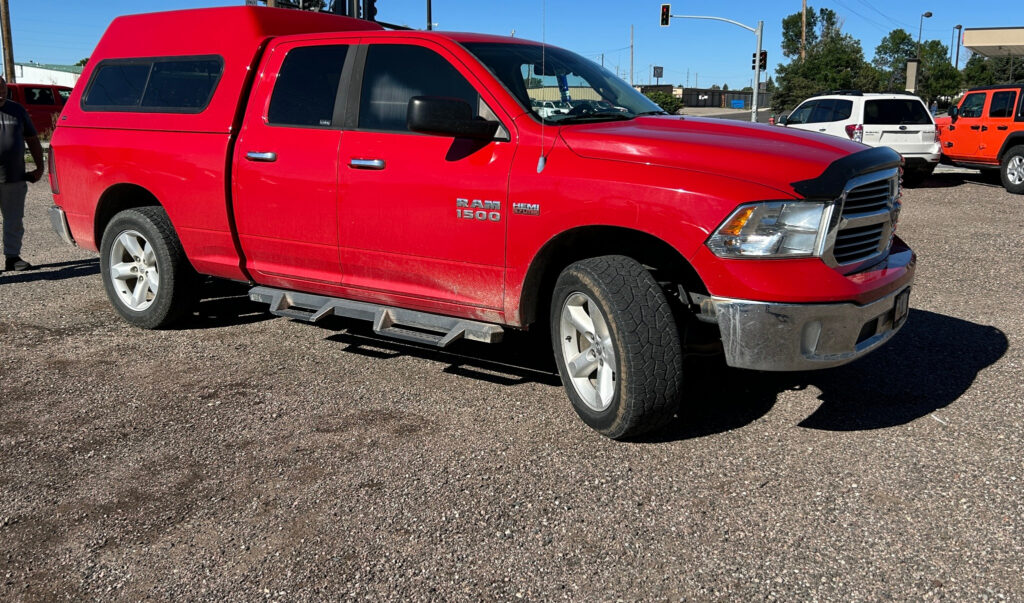 Red RAM 1500 pickup truck with a color-matched truck topper installed by TNT Customs, parked outdoors in daylight.