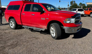 Red RAM 1500 pickup truck with a color-matched truck topper installed by TNT Customs, parked outdoors in daylight.