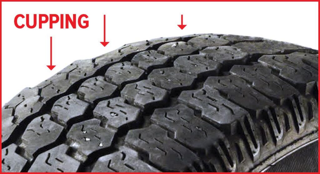 Close-up of a tire showing cupping or scalloped tread wear caused by worn shocks, struts, or suspension components.