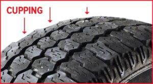 Close-up of a tire showing cupping or scalloped tread wear caused by worn shocks, struts, or suspension components.